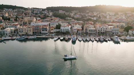 serene aerial view of a sailboat gliding past a coastal town on kefalonia island, greece