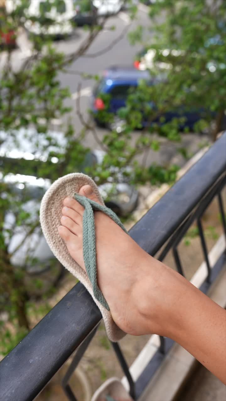 Person relaxing on a balcony wearing flip-flops