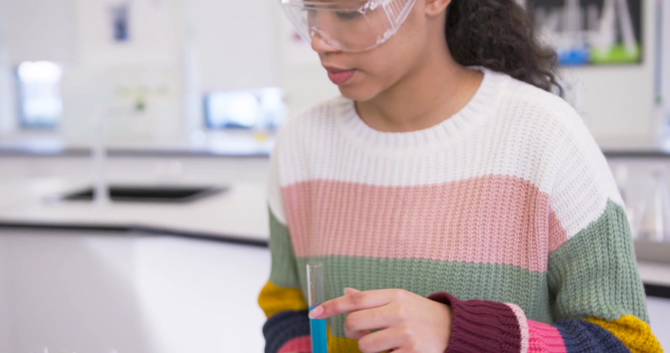 Female child sweater goggles holding tube tapping tablet placing tubes in rack using tablet in lab