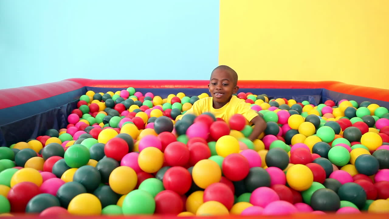 un niño lindo emergiendo de la piscina de pelota