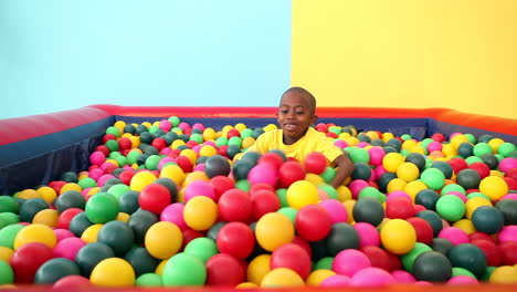 cute little boy emerging from ball pool