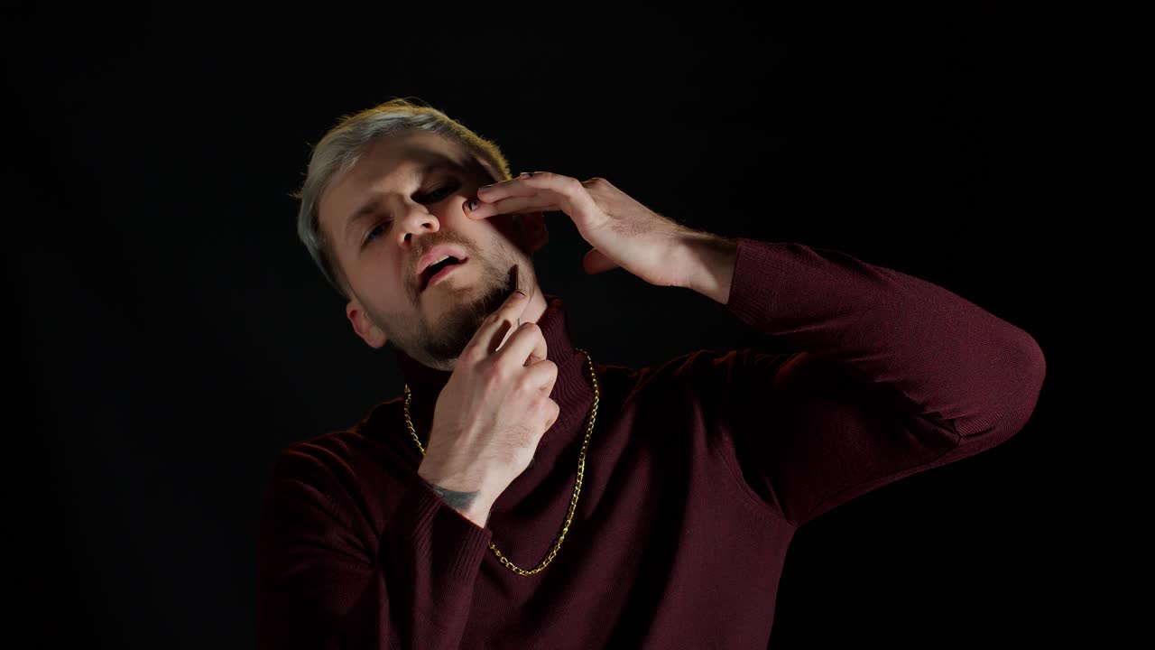 트렌디 한 스타일리시 의 옷 을 입은 면도 하지 않은 젊은 남자 의 초상화 는 검은색 배경 에 칼 을 고 면도 하고 있다