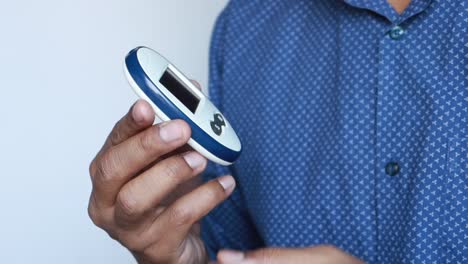 man using a blood glucose meter to check his blood sugar