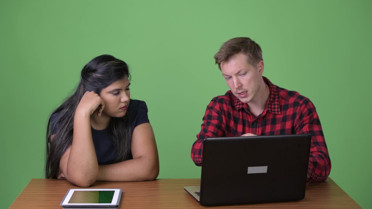 joven pareja de negocios multiétnica juntos contra un fondo verde