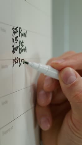 person writing on a whiteboard calendar