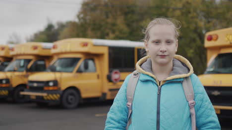 retrato de una alumna contra el fondo de un típico autobús escolar amarillo