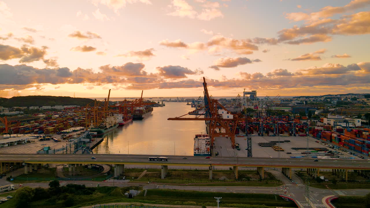 Vehicles Driving On A Bridge With Industrial Port In The Background At Dusk In Gdynia, Poland