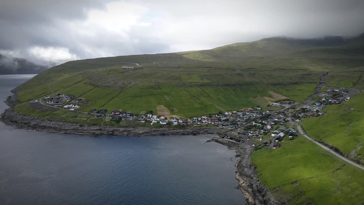 스트레이모이 섬의 거친 해안선에 있는 그림 같은 마을인 비비크 (kvívívik) 를 촬영한 드론 뷰 (drone view) 는 구름이 가득한 하늘 아래 다채로운 집, 푸른, 그리고 극적인 산을 특징으로 한다.