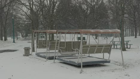 bancos vacíos afuera bajo la nieve en un parque con árboles