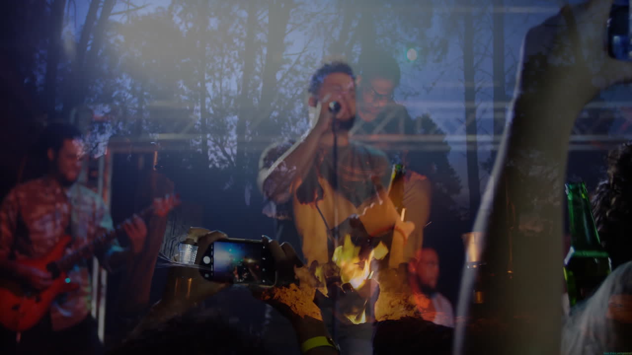 male singer holding mic singing music by campfire, audience raising smartphones, floating notes