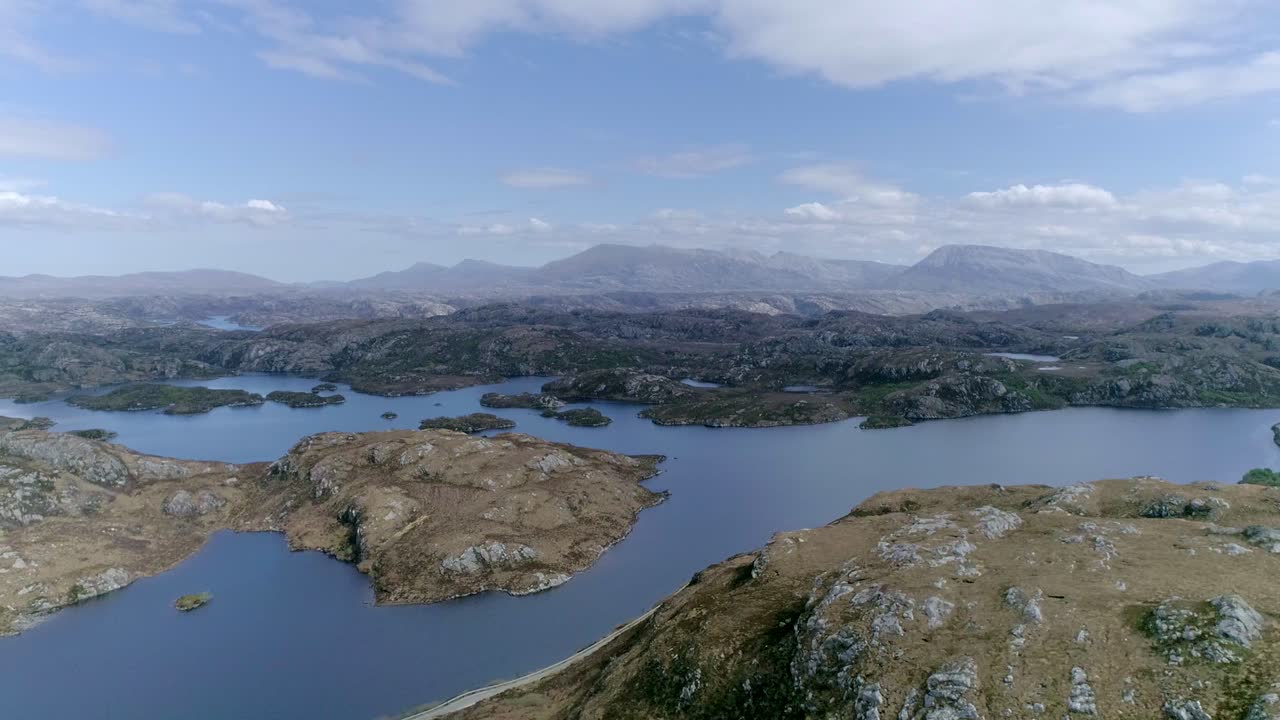 vista aérea lateral de un vasto lago con múltiples islas en una abrumadora región montañosa escocesa