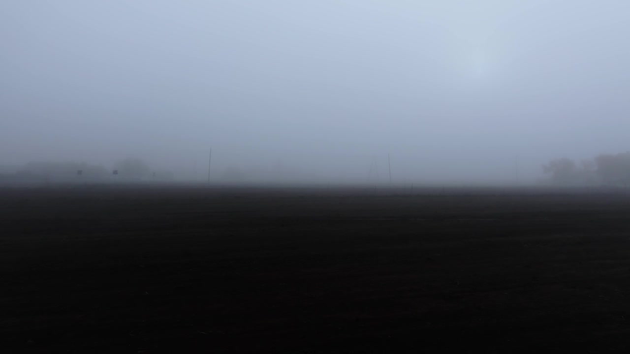 Dense fog hides an empty field creating haunting atmosphere for Halloween horror