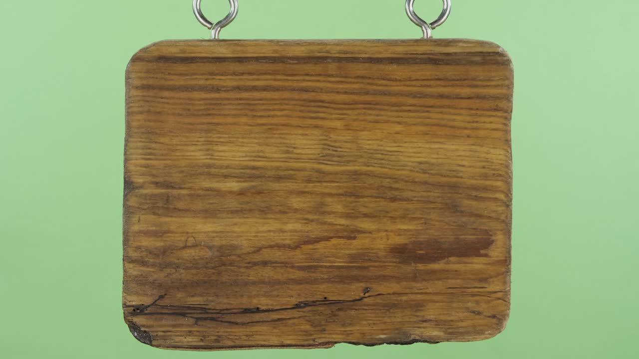 초록색 배경에 로프에 매달린 빈 나무 표지판.