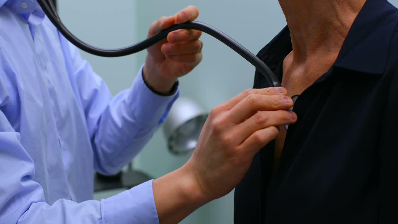 Mid section of male doctor examining a senior patient with stethoscope in the clinic 4k
