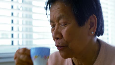 Senior-woman-having-coffee-in-living-room