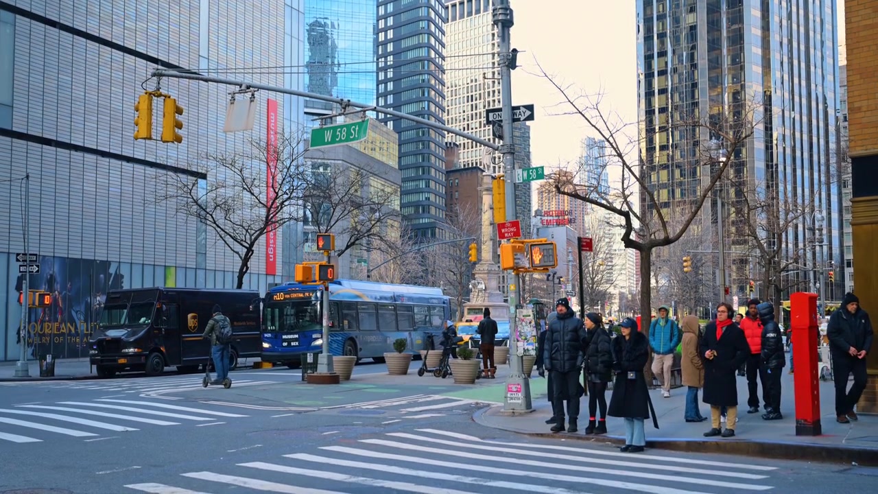New York, USA, 15 April 2026: Busy intersection at West 58th Street near Columbus Circle. Pedestrians and cyclists crossing at W 58th St with Museum of Arts and Design in background