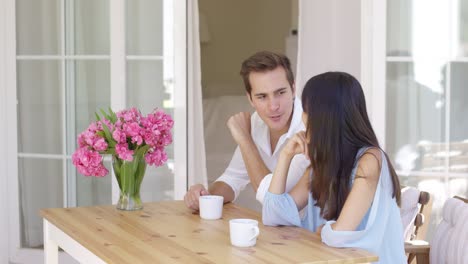 Joyful-mixed-adult-couple-sitting-at-table