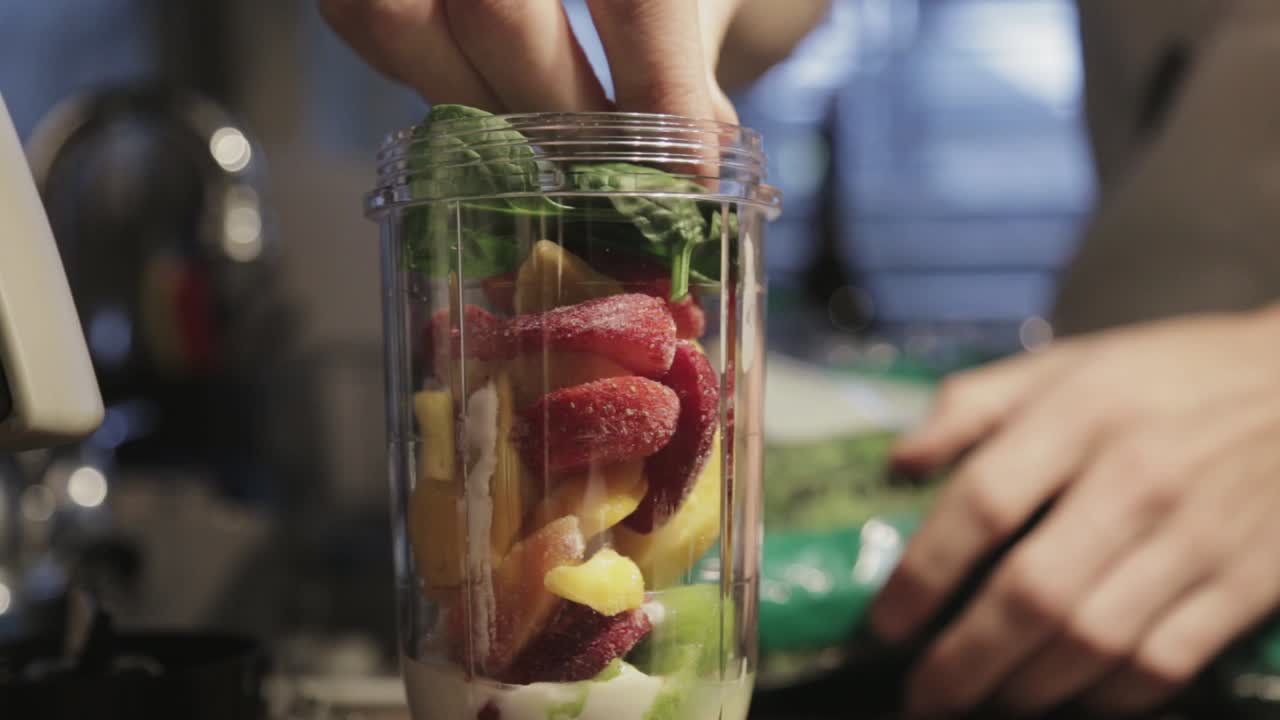 Aggiungere frutta e verdura fresca nel contenitore del frullatore per uno smoothie - Primo piano