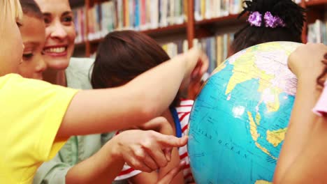 alumnos y profesores mirando el globo en la biblioteca