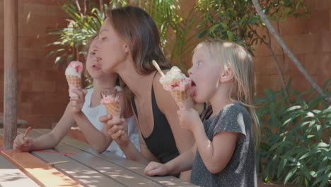 una mujer joven y dos niños comiendo helado.