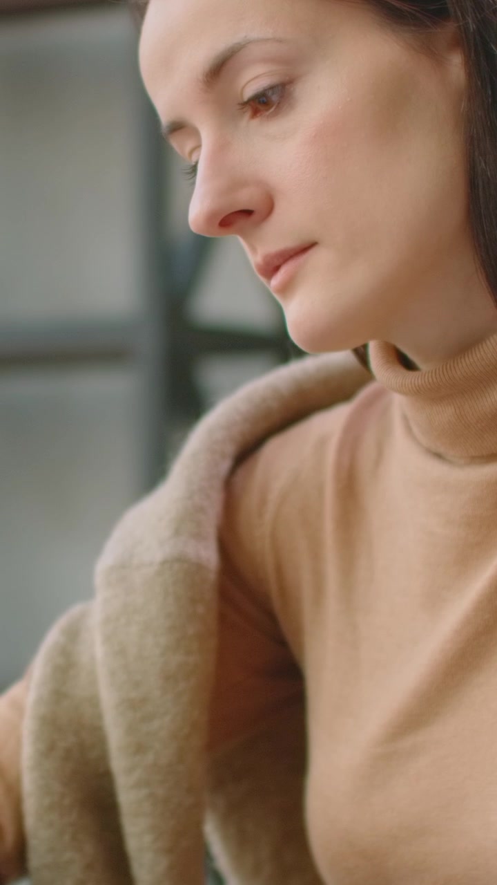Thoughtful Woman in Beige Turtleneck Looking Down