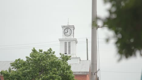 Detail-wide-shot-of-White-Church-clock-tower-during-a-cloudy-day-with-power-lines