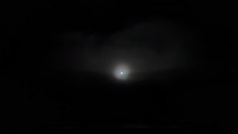 aerial footage taken from a jet cockpit of the full moon and its halo while flying under a layer of clouds. 4k 60fps
