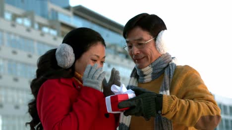 couple in warm clothing holding gift