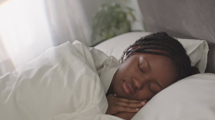 Giovane donna di colore che dorme in un letto bianco