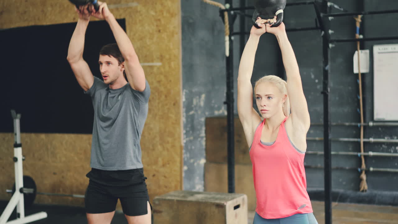 Couple Working Out with Kettlebells in Gym