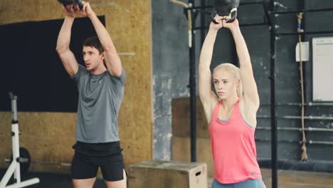 couple working out with kettlebells in gym