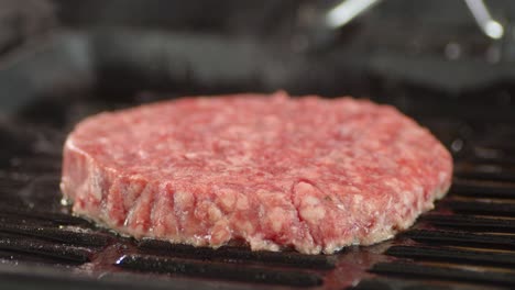 raw beef burger is fried in a frying pan.