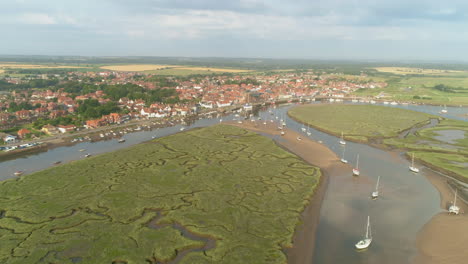 establishing drone shot of wells-next-the-sea coastal town with salt marsh and sailing boats in north norfolk uk east coast