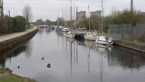 Kleine-Segelboote,-Die-Auf-Einem-Schmalen-Jachthafenkanal-In-Der-Ländlichen-Landschaft-Festgemacht-Sind