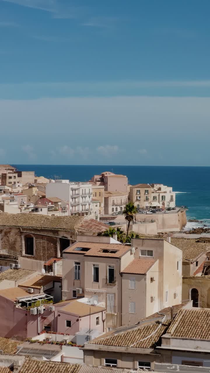 Vertical aerial drone shot of Ortigia island. Old town in Syracuse. Flying low over historic architecture buildings in charming Italian town. UNESCO world heritage site in Sicily.