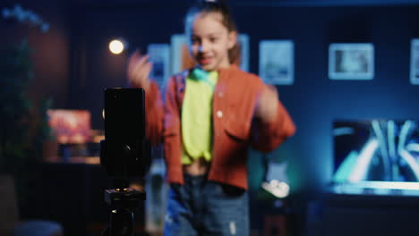 focus shot on smartphone on tripod used by kid in blurry background doing viral dance choreography