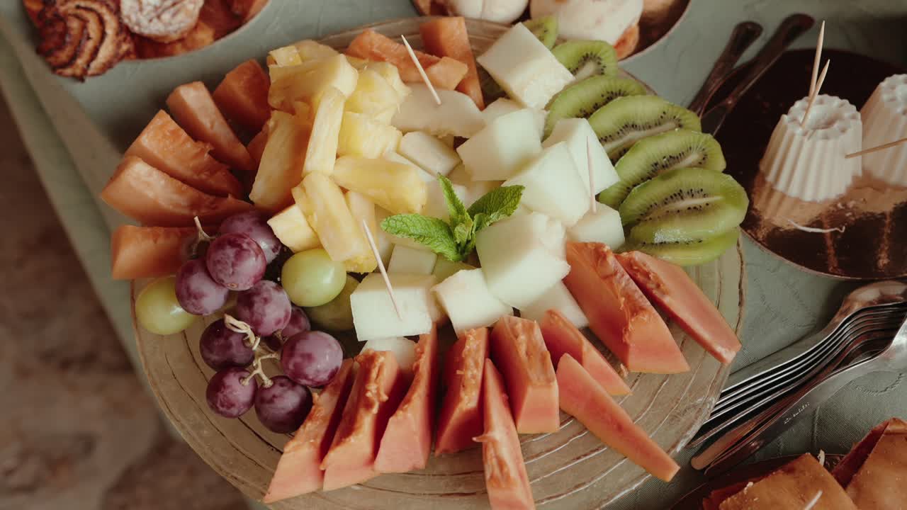 colorful arrangement of sliced fruits including papaya kiwi grapes and pineapple on a tray