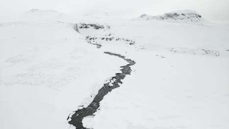 Man-Walking-On-A-Cold-Winter-Day-Towards-Svodufoss-Waterfall-In-Iceland