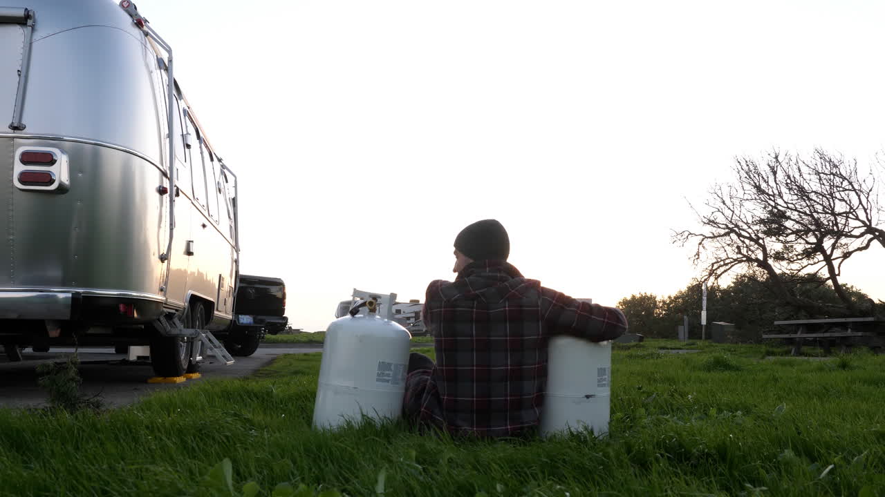 여행 트레일러로 프로판 탱크를 껴안는 남자