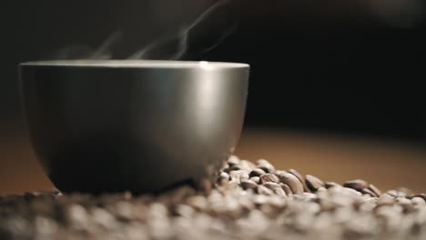 steaming cup of coffee on coffee beans
