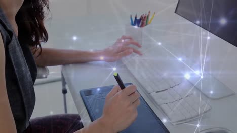 animation of illuminated connected dots over asian woman sketching using graphics tablet