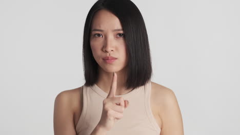 asian woman making silence gesture on camera.