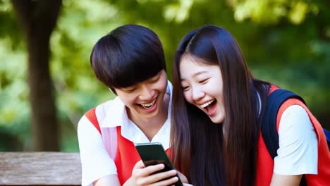 십대 들 이 공원 에서 드폰 으로 무언가 에 웃고 있다