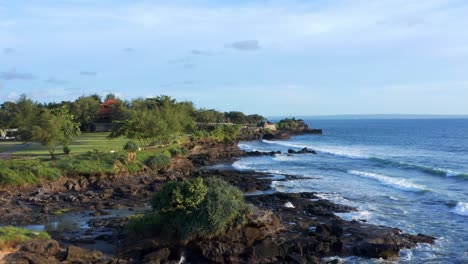 Foamy-Waves-Splashing-Rocky-Shore-Near-Tanah-Lot-Temple-In-Bali,-Indonesia---aerial-drone-shot