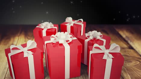 animación de nieve cayendo sobre los regalos de navidad sobre un fondo de madera y negro
