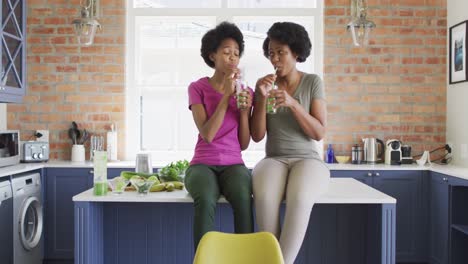 Glückliche-Afroamerikanische-Mutter-Und-Tochter-Trinken-Gesundes-Getränk-In-Der-Küche