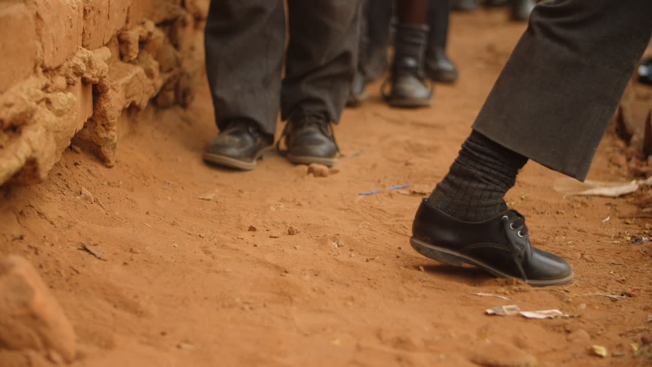 Scarpe da scuola degli alunni mentre camminano sul terreno nell'Africa rurale
