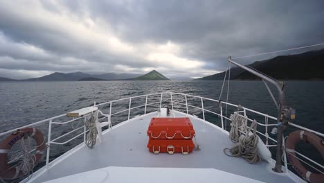 SLOWMO---Front-panorama-view-of-cruise-boat-with-of-ocean,-hills-and-cloudy-sky-in-background