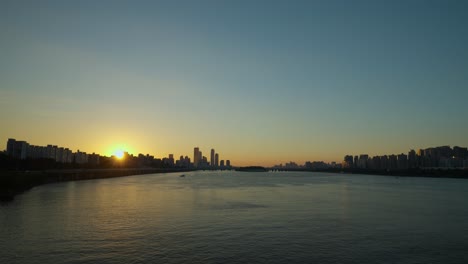 seoul sunset - sun setting behind youido skyscraper buildings and sunlight reflection in han river water - view from dongjak bridge