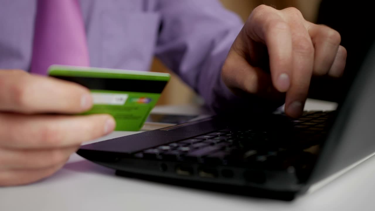 un hombre de negocios con una camisa púrpura y corbata está haciendo un pago a la banca por internet. compras en línea con tarjeta de crédito en la computadora portátil.